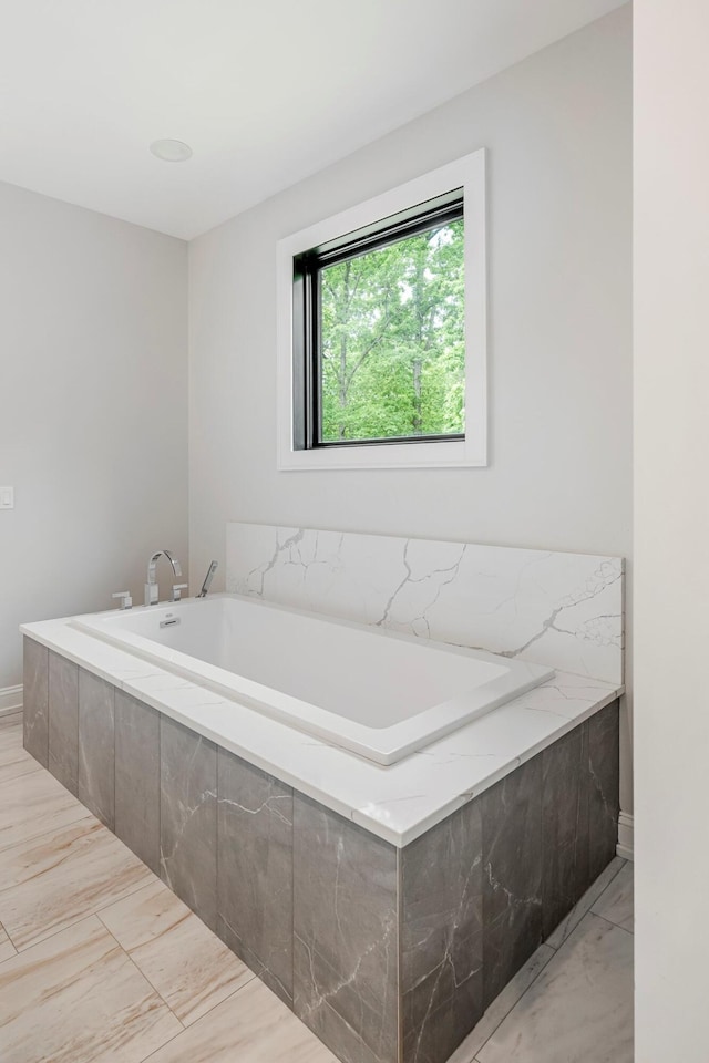 bathroom featuring marble look tiles and a garden tub