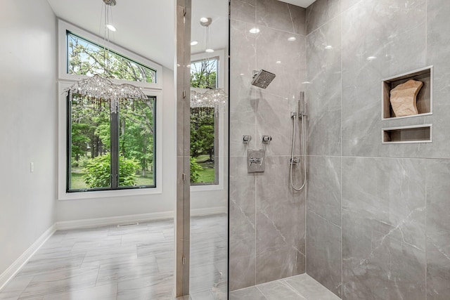 bathroom with tiled shower, baseboards, and marble look tiles