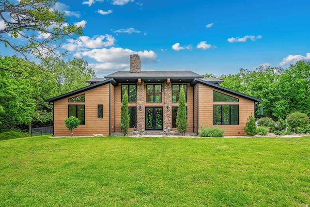 rear view of house featuring a lawn, a chimney, and french doors