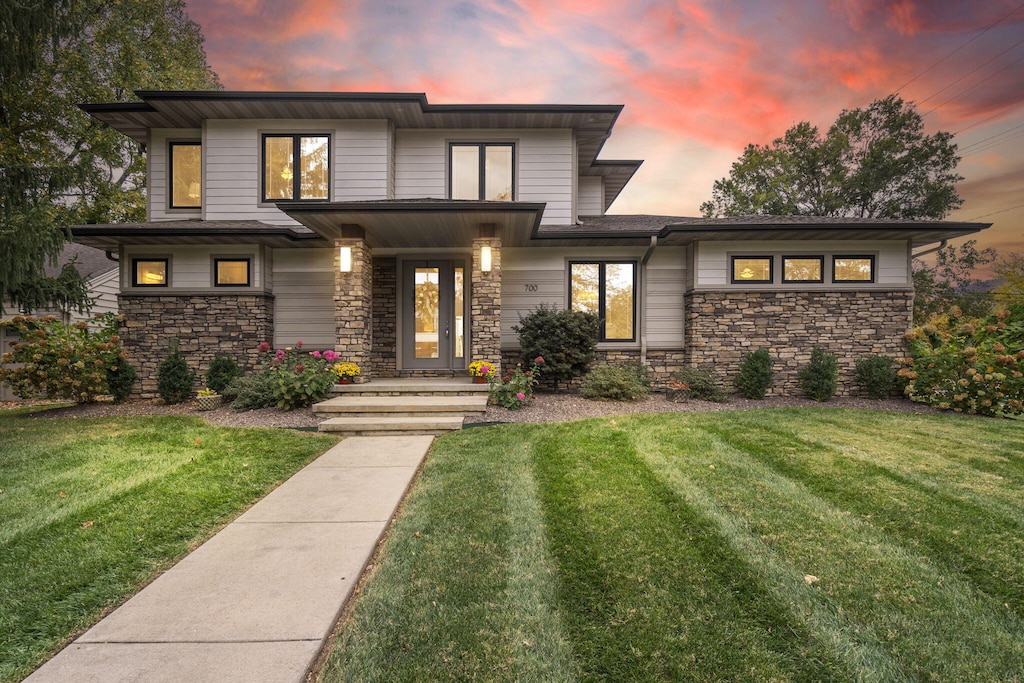 prairie-style house featuring a front yard and stone siding