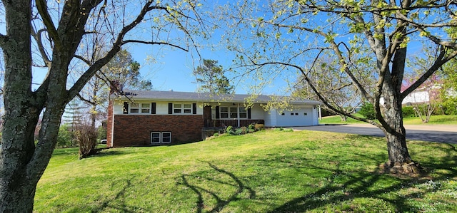 single story home featuring a front yard, an attached garage, aphalt driveway, and brick siding