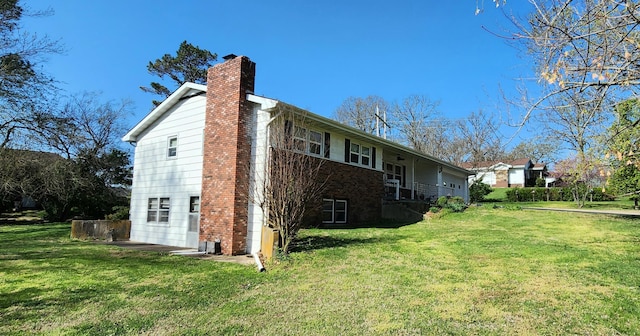 view of side of home with a chimney and a yard