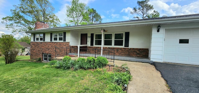 ranch-style home featuring a chimney, brick siding, a front lawn, and an attached garage