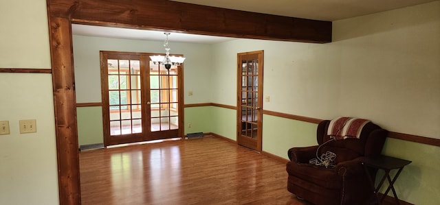 doorway to outside featuring beamed ceiling, french doors, baseboards, wood finished floors, and a notable chandelier