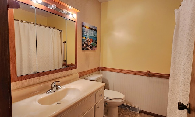 bathroom featuring tile patterned floors, wainscoting, toilet, vanity, and visible vents