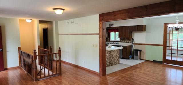 interior space with a chandelier, baseboards, an upstairs landing, and light wood-style flooring