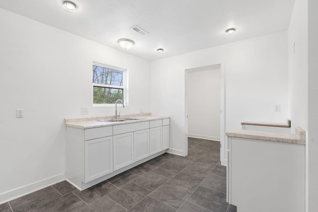 341 N Golden Ave, Springfield, MO 65802 - kitchen featuring visible vents, baseboards, a sink, light countertops, and white cabinetry
