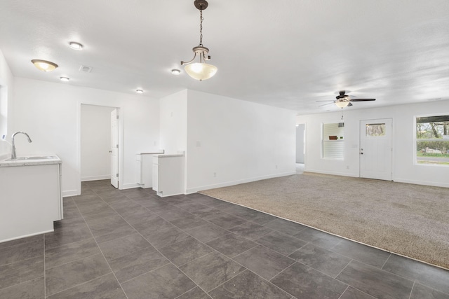341 N Golden Ave, Springfield, MO 65802 - unfurnished living room with visible vents, baseboards, a sink, a ceiling fan, and dark tile patterned flooring