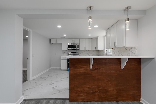 2120 N Broadway Ave, Springfield, MO 65803 - kitchen featuring baseboards, a breakfast bar, a peninsula, light countertops, and appliances with stainless steel finishes