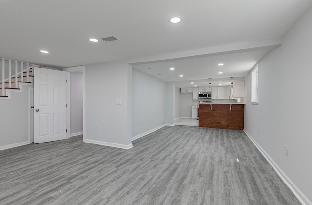 2120 N Broadway Ave, Springfield, MO 65803 - unfurnished living room featuring recessed lighting, stairway, visible vents, and light wood-type flooring