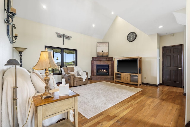 living room with baseboards, a tiled fireplace, recessed lighting, wood-type flooring, and high vaulted ceiling