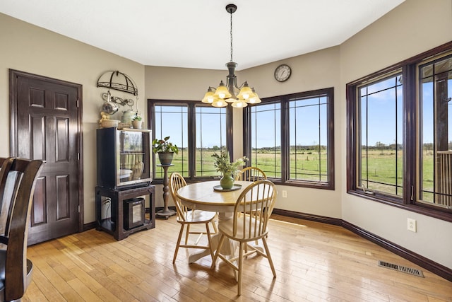 dining area with light wood-style flooring, an inviting chandelier, baseboards, and visible vents