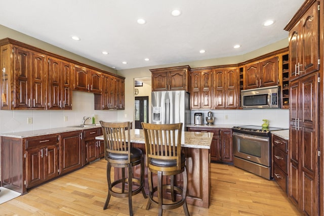 kitchen with light wood finished floors, recessed lighting, stainless steel appliances, backsplash, and a kitchen island