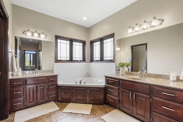 full bath featuring two vanities, a bath, and a sink