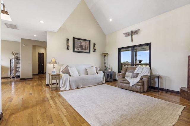 living room with visible vents, baseboards, light wood-type flooring, and high vaulted ceiling