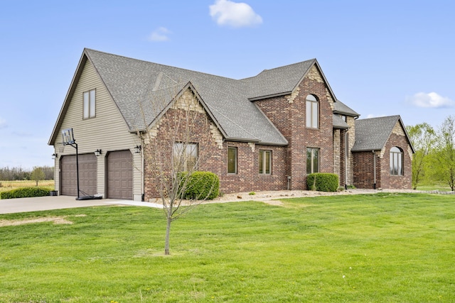 view of front facade with concrete driveway, roof with shingles, an attached garage, a front yard, and brick siding