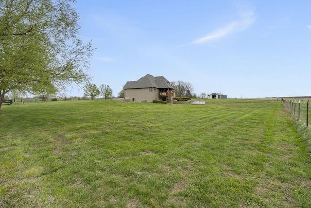view of yard with fence and a rural view