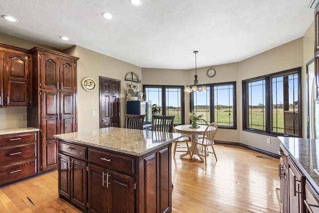 kitchen featuring a notable chandelier, recessed lighting, light stone countertops, decorative light fixtures, and light wood-style floors