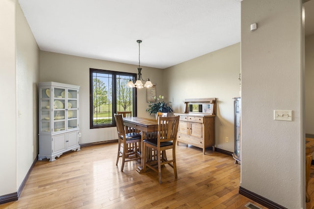 dining room with light wood finished floors, baseboards, and an inviting chandelier