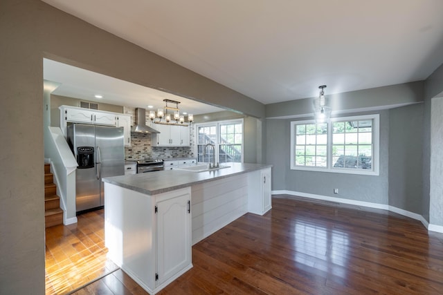 kitchen featuring wall chimney exhaust hood, appliances with stainless steel finishes, white cabinetry, and a sink