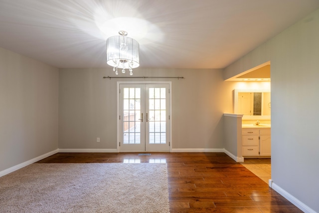 interior space featuring french doors, wood finished floors, an inviting chandelier, and a healthy amount of sunlight