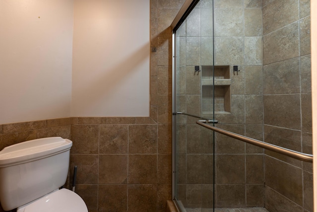 full bathroom featuring a shower stall, a wainscoted wall, and toilet