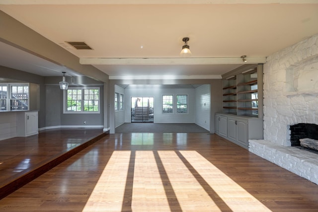 unfurnished living room with baseboards, wood finished floors, visible vents, and a fireplace