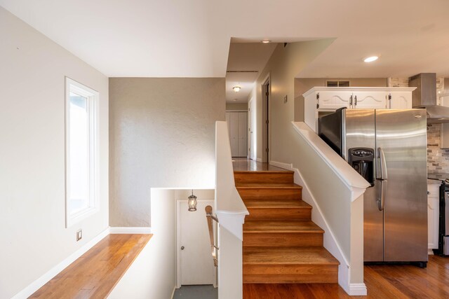 staircase with baseboards, wood finished floors, visible vents, and recessed lighting