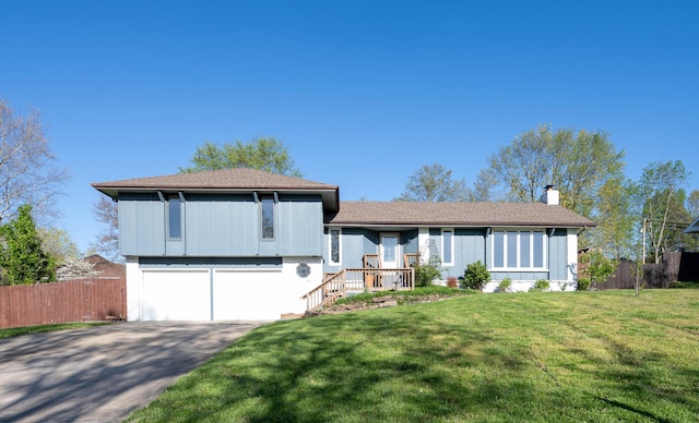 tri-level home with a chimney, fence, aphalt driveway, and a front yard