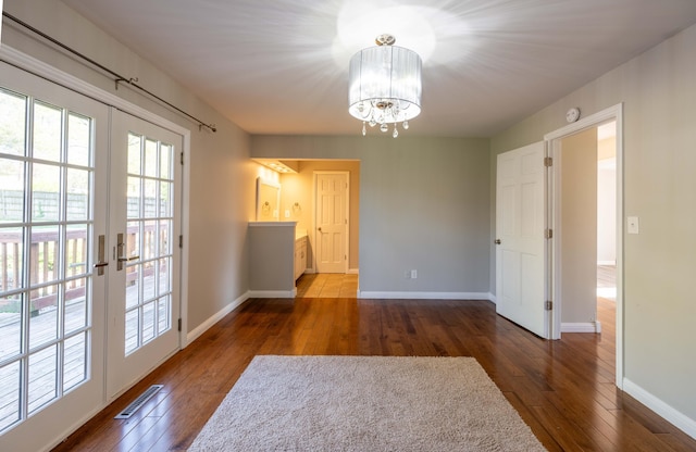 unfurnished dining area with french doors, baseboards, visible vents, a chandelier, and wood-type flooring