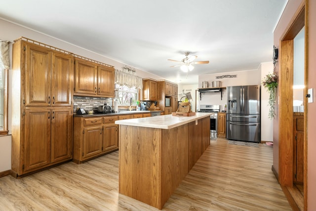 940 Industrial Dr, Neosho, MO 64850 - kitchen featuring stainless steel appliances, light wood-type flooring, a ceiling fan, brown cabinetry, and a kitchen island