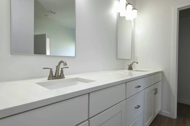 5896 Applewood Ave, Springfield, MO 65810 - bathroom featuring double vanity, visible vents, wood finished floors, and a sink