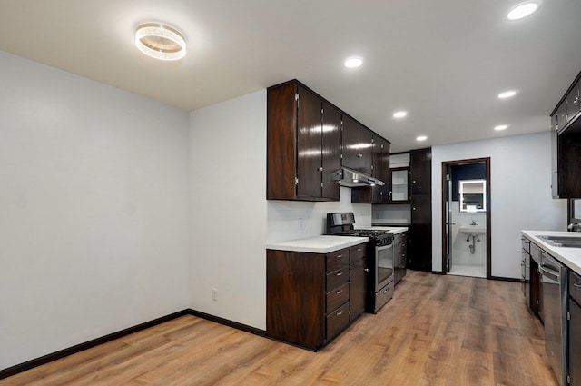 704 King St, Mount Vernon, MO 65712 - kitchen featuring under cabinet range hood, stainless steel appliances, light countertops, light wood-style floors, and dark brown cabinetry