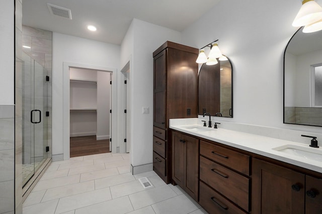 full bathroom with visible vents, a sink, double vanity, and a stall shower