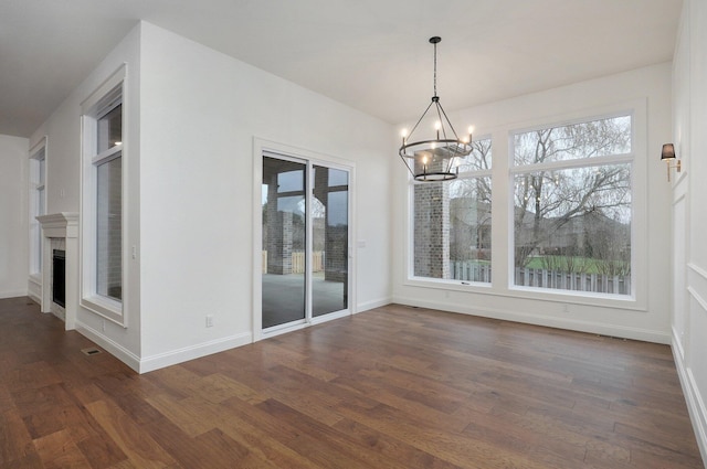 unfurnished dining area featuring dark wood-style floors, a chandelier, and a healthy amount of sunlight