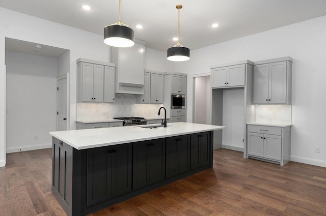 kitchen featuring decorative backsplash, an island with sink, a sink, and light countertops