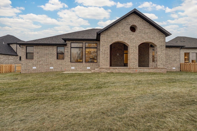 back of house with fence, brick siding, and a yard
