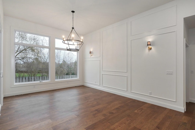 unfurnished dining area with baseboards, visible vents, a notable chandelier, and dark wood-style flooring