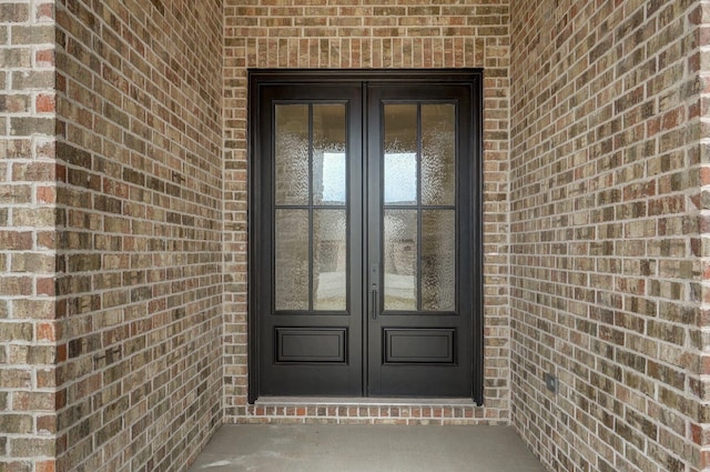 doorway to property featuring brick siding and french doors