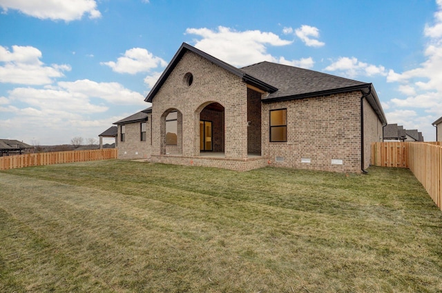 rear view of house featuring a shingled roof, a fenced backyard, a yard, a patio, and brick siding