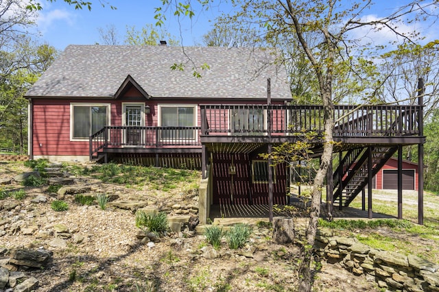 rear view of property with roof with shingles, driveway, a garage, stairway, and a deck