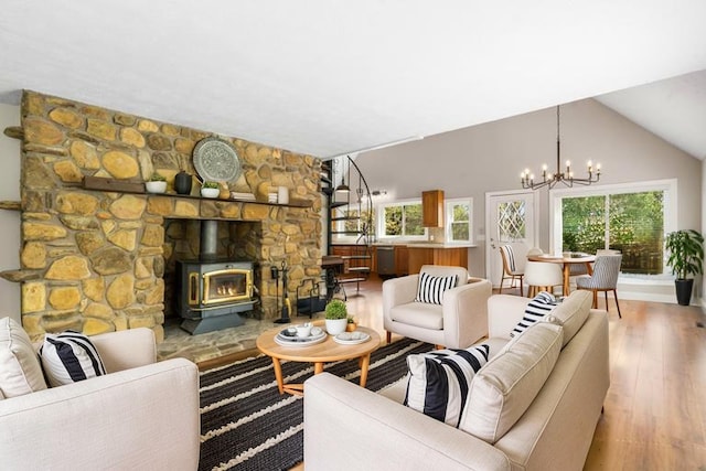 living area featuring a chandelier, wood finished floors, a wood stove, and lofted ceiling