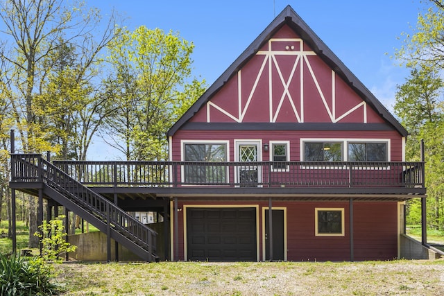 rear view of property with a deck, stairs, and a garage