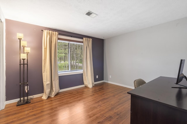 home office featuring dark wood-style floors, baseboards, a textured ceiling, and visible vents