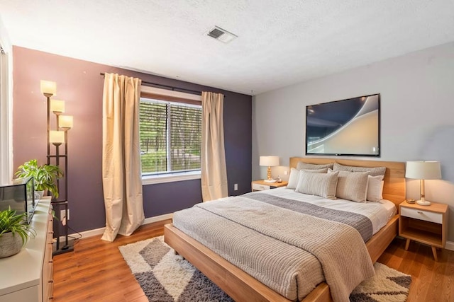 bedroom with baseboards, wood finished floors, and visible vents