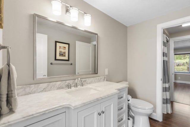 bathroom featuring wood finished floors, vanity, baseboards, toilet, and visible vents
