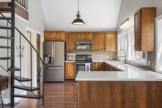 kitchen with stainless steel appliances, a peninsula, backsplash, brown cabinetry, and light countertops