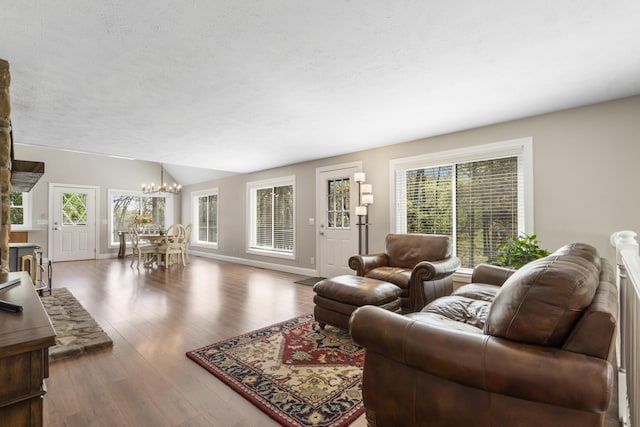 living room with baseboards, a notable chandelier, wood finished floors, and lofted ceiling