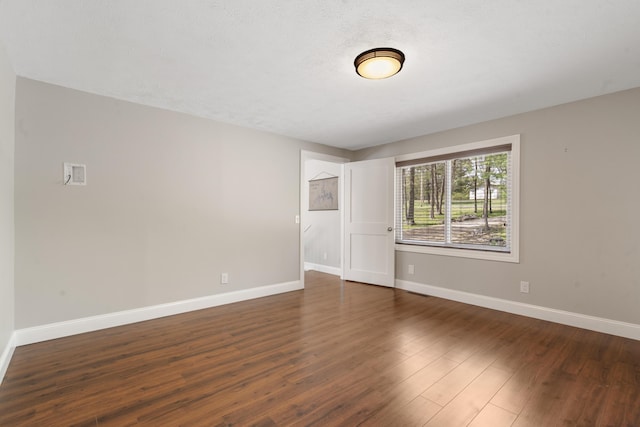 empty room featuring baseboards and dark wood-style floors