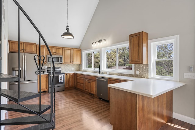 kitchen with a peninsula, backsplash, brown cabinetry, and stainless steel appliances